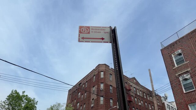 New York CityAlternate side parking street sign in urban city area. Traffic regulation sign with parking rules on city street against residential or commercial buildings background