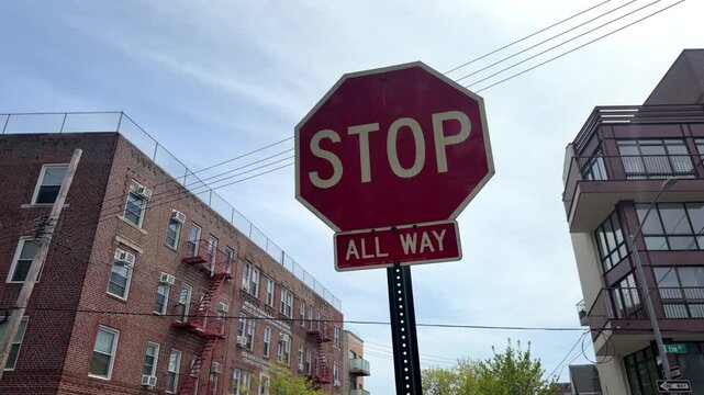 Stop road sign against blue sky and urban buildings background. Red traffic stop sign in city street with clear sky, architecture, and transportation concept.