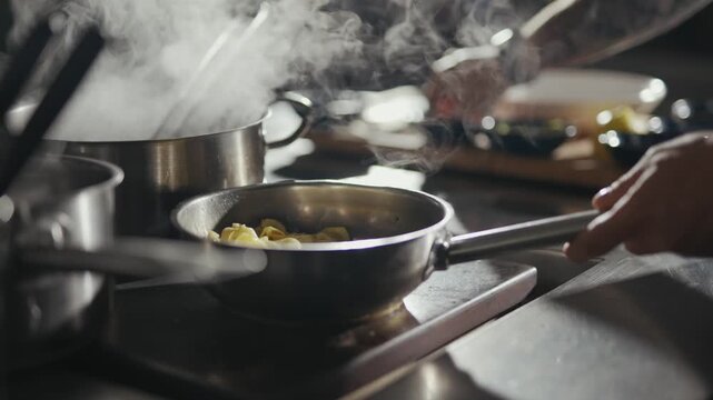 Steam rises from sizzling pans in a bustling kitchen. Tattooed hands stir, adjust, and tend to simmering dishes. Focus is sharp, with soft background blur to emphasize action. Ideal for food, culinary