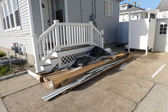 Trash and extra siding in a pile by steps going to a house