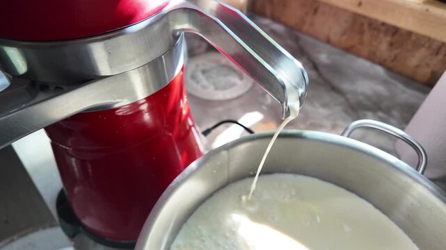 Top view of milk separator producing cream and skim milk flowing into containers. Dairy processing, food production and traditional farming technology concept. High quality 4k footage