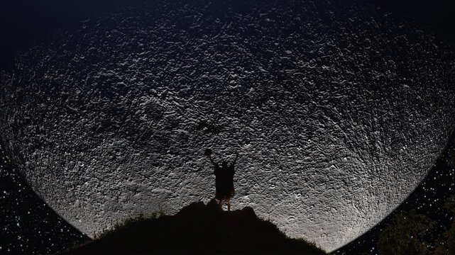 Man on a mountain top jumping in excitement when watching the space station transit the lunar surface