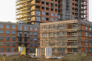 Different stages of building facade construction and finishing.  grey base coats and initial insulation layers. residential construction site metal scaffolding where windows © ArieStudio