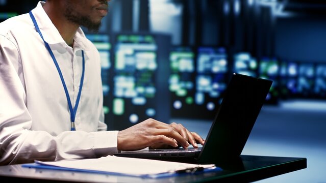 Engineer preventing strain on data center infrastructure caused by artificial intelligence applications driving up power usage. African american expert maintenancing servers doing intense computations