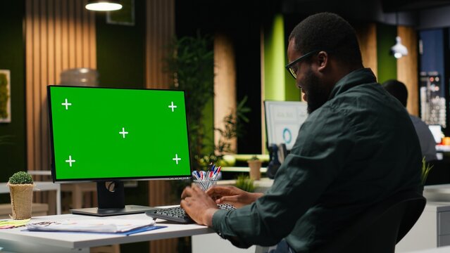 Green screen on computer monitor with black general director ensuring success, working in office after hours. Brainstorming solutions for development with a fruitful growth vision.