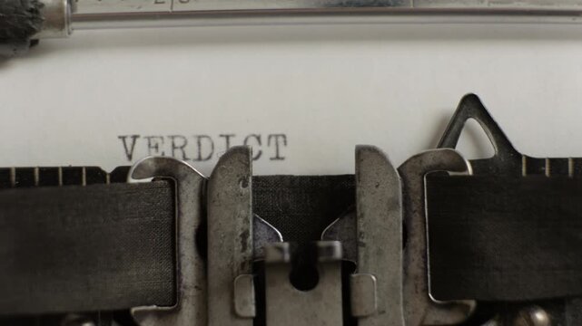 Verdict being typed on vintage typewriter on sheet of paper close-up