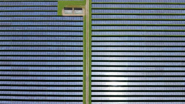 Aerial view of Tutbury solar energy farm with rows of photovoltaic panels and a central access path in Tutbury, England, United Kingdom.