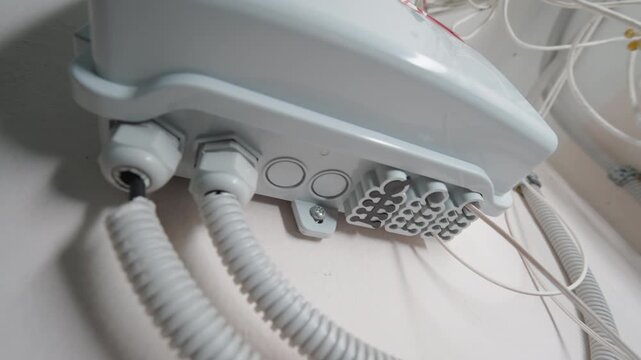 Bottom-Up Close-Up View: Optical Network Distribution Box Mounted on Wall with Connected Cables | Fiber Internet Infrastructure Equipment