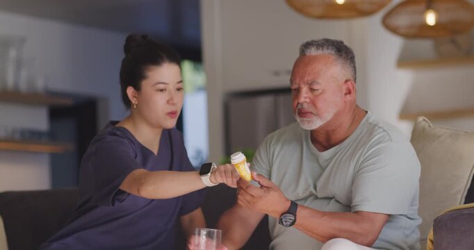 Caregiver woman offering yellow pill bottle, guiding senior man reading label, confirming dose