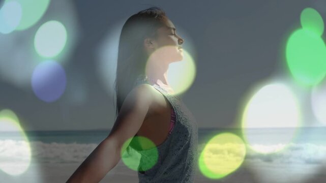 Vertical video: Woman inhaling, opening arms, tilting on beach for wellness, bokeh forming over her