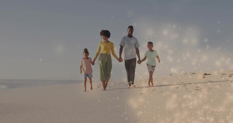 Fototapeta premium Walking family of four holding hands along shore near ocean, leaving footprints in bright clothes