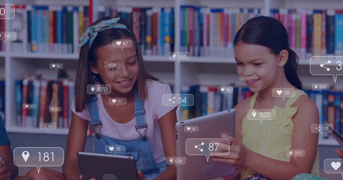 Holding two students tapping tablets at classroom shelves, denim overalls, yellow top, social icons
