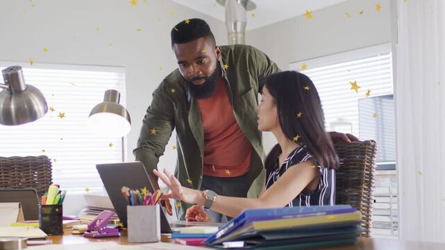 Woman pointing at laptop screen, partner leaning in, both reviewing business project with snack