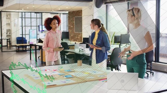 Left woman pointing at layout triggers team checking tablet and using laptop, finalizing design