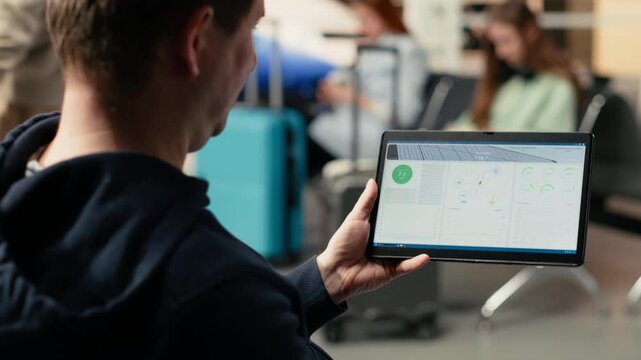 Renewable energy, photovoltaic panels performance, digital nomad in airport, checking sustainable power systems on laptop in waiting lounge. International travel with alternative energy planning.