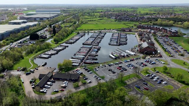 Aerial view of Barton Marina with narrowboats docked in rows, surrounded by parking lots and green fields in Barton-under-Needwood, England, United Kingdom.