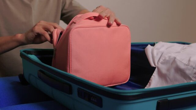 Hands opening pouch. Unzipping red case with care. Person arranging gadgets in soft fabric pouch. Close view of hands organizing electronic accessories in pouch