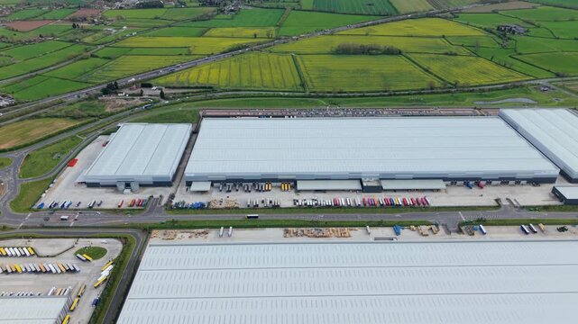 Aerial view of Appleby Magna Industrial Park with large warehouses, loading bays, and trucks surrounded by green fields in Appleby Magna, England, United Kingdom.