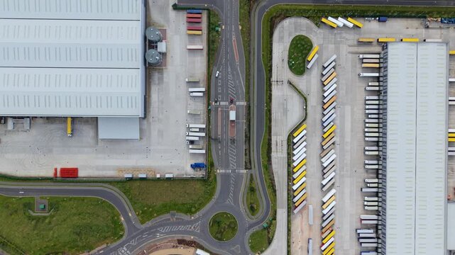 Aerial view of Appleby Magna Industrial Park with rows of parked trucks, large warehouses, and a central roundabout in Appleby Magna, England, United Kingdom.