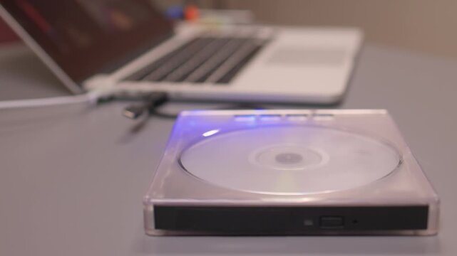 Close examination of fingers setting up DVD player with spinning disc. Focused shot of hands configuring compact DVD device with illuminated light and rotating disc