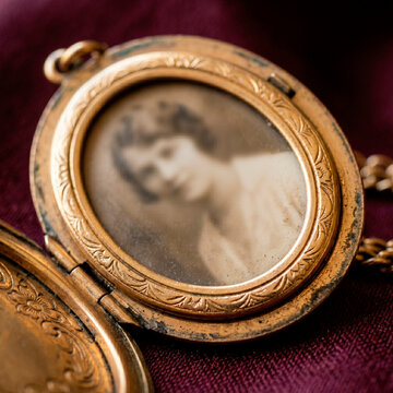 Relicario de oro antiguo abierto con fotograf&iacute;a sepia de una mujer joven