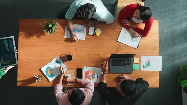 Top down view of manager holds tablet display increasing sales and placed on meeting table. Group of diverse business team clapping hands to celebrate successful product at meeting room Convocation.