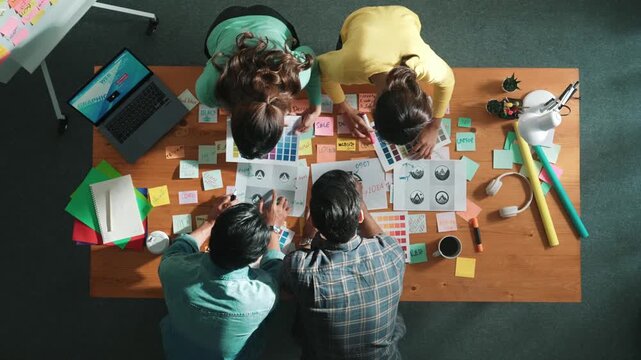 Top view of business team write graphic logo on meeting table with colorful sticky notes and design while explain idea. Project manager sharing idea and explain concept art to smart team. Symposium.