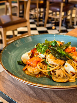 Close up, Stir-fried spicy spaghetti with mixed seafood and Thai basil, fusion cuisine  in a blue ceramic plate.
