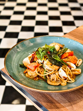 Close up, Stir-fried spicy spaghetti with mixed seafood and Thai basil, fusion cuisine  in a blue ceramic plate.