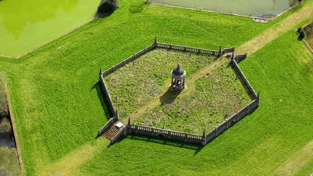 Aerial view of the historic monument at Swithland Reservoir surrounded by a hexagonal stone wall and lush green grass in Leicestershire, England, United Kingdom.