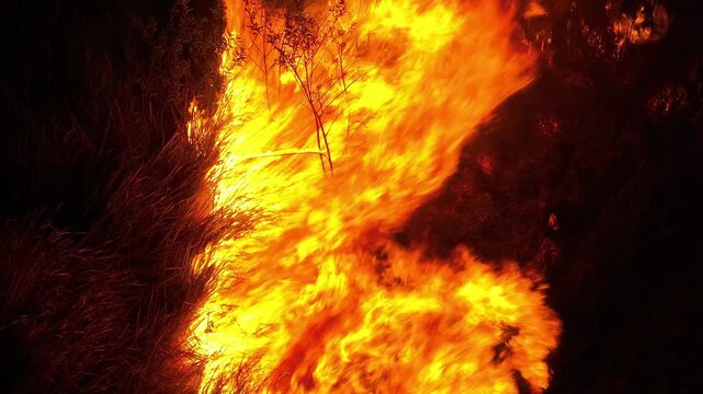 Drone view of severe wildfire at night symbolizes climate crisis pressures, hotter and drier conditions, uncontrolled fire spread, and urgent concerns over increasing wildfire disasters. Thailand. 4k.