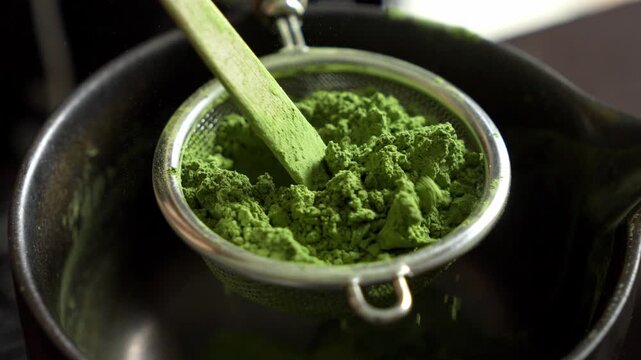 Close-up of green ceremonial matcha powder being spread through a sieve for a traditional Japanese tea ceremony. Authentic preparation of healthy organic tea