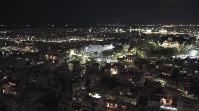 Stunning aerial footage capturing the illuminated cityscape of piraeus at night, showcasing the iconic Veakio municipal theater, bustling streets, and the glowing harbor in the distance