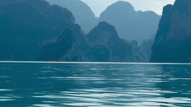 Giant limestone cliffs at Cheow Lan Lake, Thailand, resembling the mystical Avatar mountains. Breathtaking view of colossal karst formations rising from deep blue waters in Khao Sok National Park.