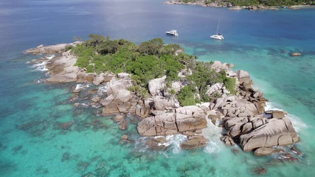 Panning down drone of cocos island, docked catamaran and lux yacht, lush untouched nature, granite stones, clear turquoise water, Seychelles 004 30fps