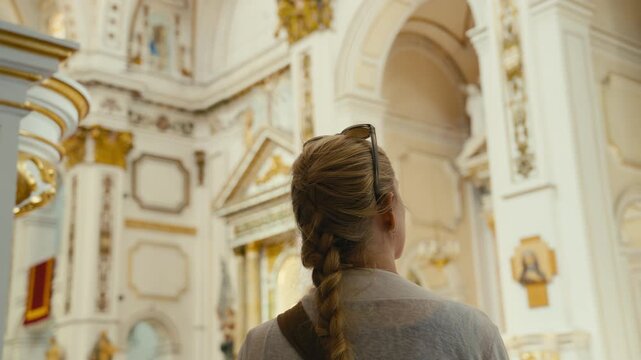 A woman stands inside an ornate church in Altea, Spain, admiring the elegant architecture and golden details. Cultural travel moment with a calm and reflective atmosphere.