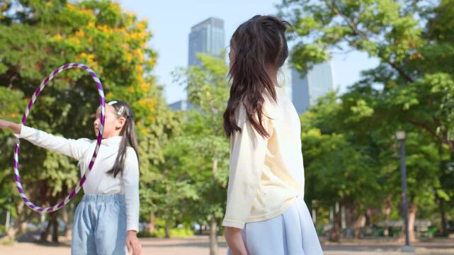 Two Asian Girls Playing with a Hula Hoop in a City Park