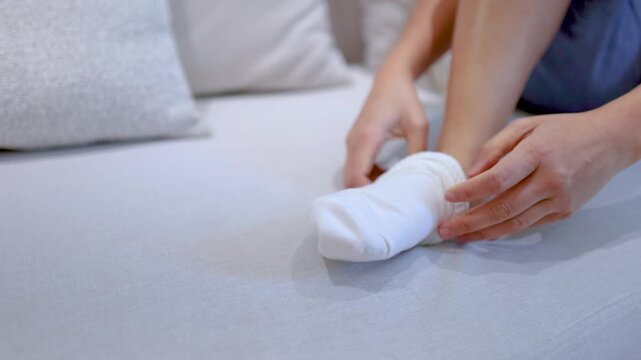 Close Up of Woman Putting on White Socks While Sitting on Bed