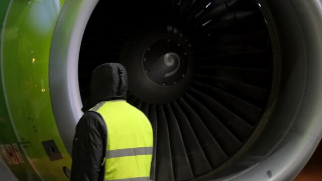 Airplane jet aircraft engine technic man inspection. Airport terminal technician worker man airline maintenance ground crew aircraft. Safety at evening night.