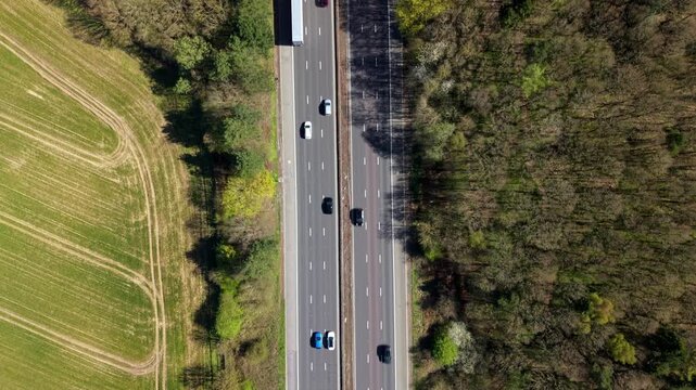 Aerial view of traffic on the M1 motorway passing between green fields and woodland in Leicestershire, England, United Kingdom.