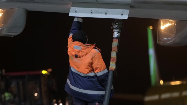 Airplane aircraft fueling. Airport worker technician man refueling aircraft plane. Terminal airline maintenance crew aviation kerosene fuel. Preparing for departure Evening night