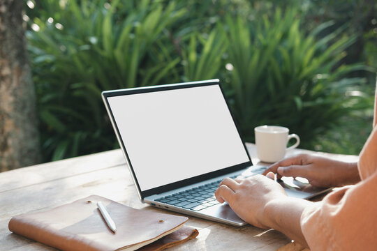 Remote work lifestyle in natural morning light with laptop on wooden outdoor table, focused typing hands, productivity and calm workspace environment with coffee and notebook in garden setting