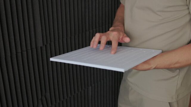 Soundproofing test on acoustic board. Evaluating sound insulation with acoustic panel testing. Technician assesses soundproofing effectiveness of acoustic panels in studio