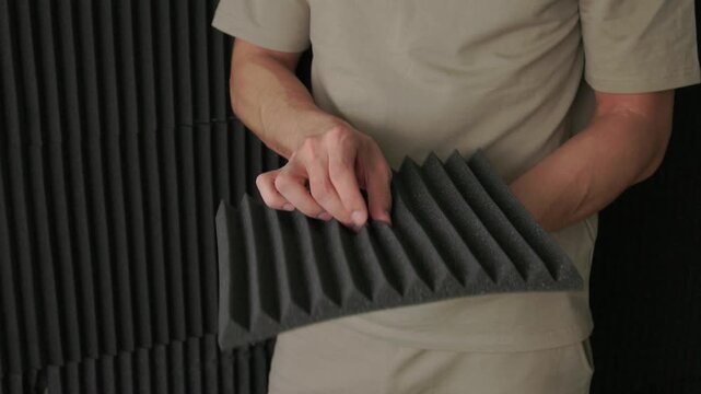 Soundproofing test on acoustic board. Evaluating sound insulation with acoustic panel testing. Technician assesses soundproofing effectiveness of acoustic panels in studio