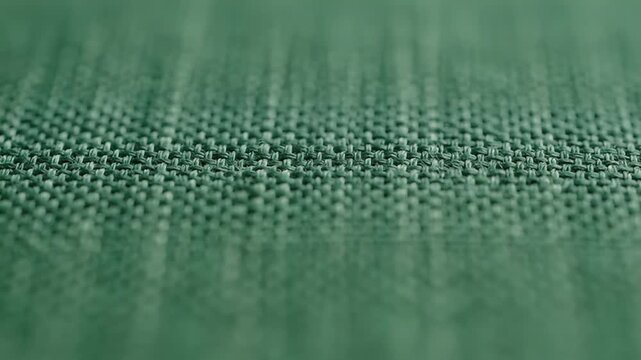 Close-up of textured green woven fabric with shallow depth of field and soft focus