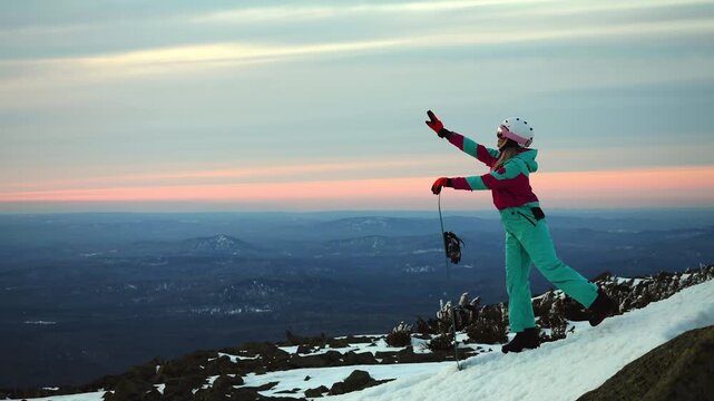 Happy female snowboarder posing on mountain slope enjoying winter sunset freedom lifestyle and adventure outdoors in snowy landscape.