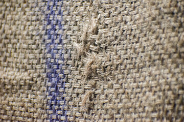 Fototapeta premium Close up of frayed burlap sack texture with blue stripe and rustic jute fabric.