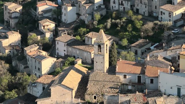 Aerial view of the historic stone houses and church bell tower of Capestrano surrounded by lush greenery Capestrano, Abruzzo, Italy.