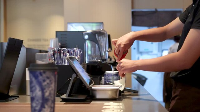 Asian Barista Using Scissors to Open Product at Bubble Tea Shop Counter