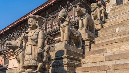 Obraz premium Beautiful Newar architecture. Sculptures of a woman, a child, a rhinoceros, a horse, and a lion are installed along the stone staircase. Vatsala Durga Temple. Barred windows on the facade. Nepal.